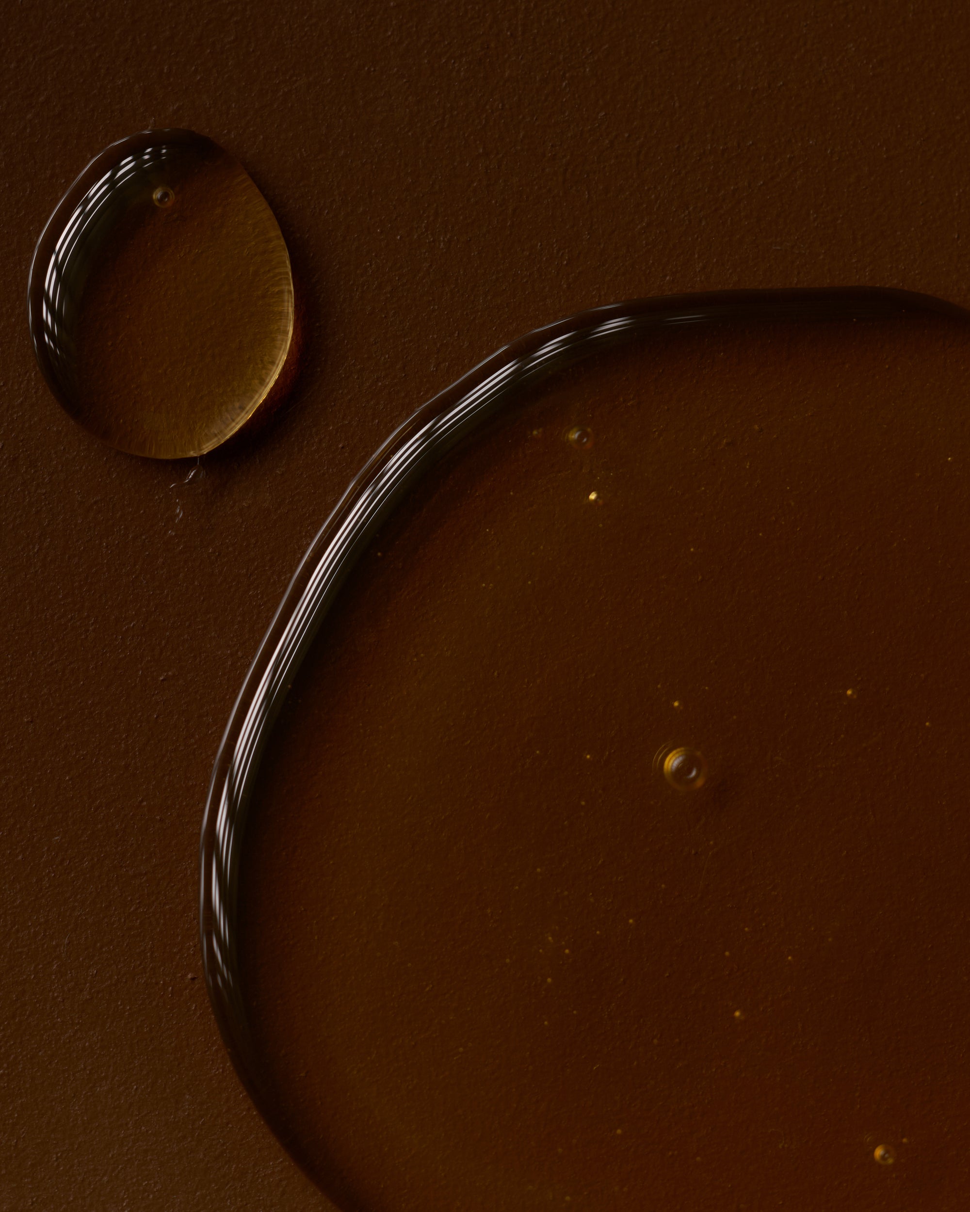 Close-up of a chocolate surface with a droplet and a curved line.