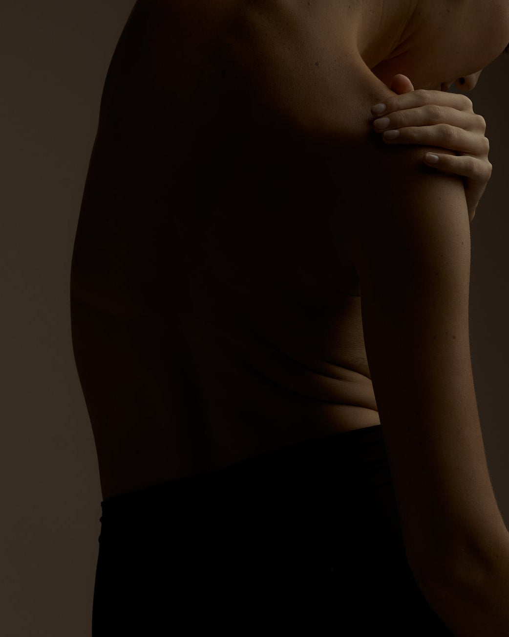 Silhouette of a person with arms crossed on a dark background