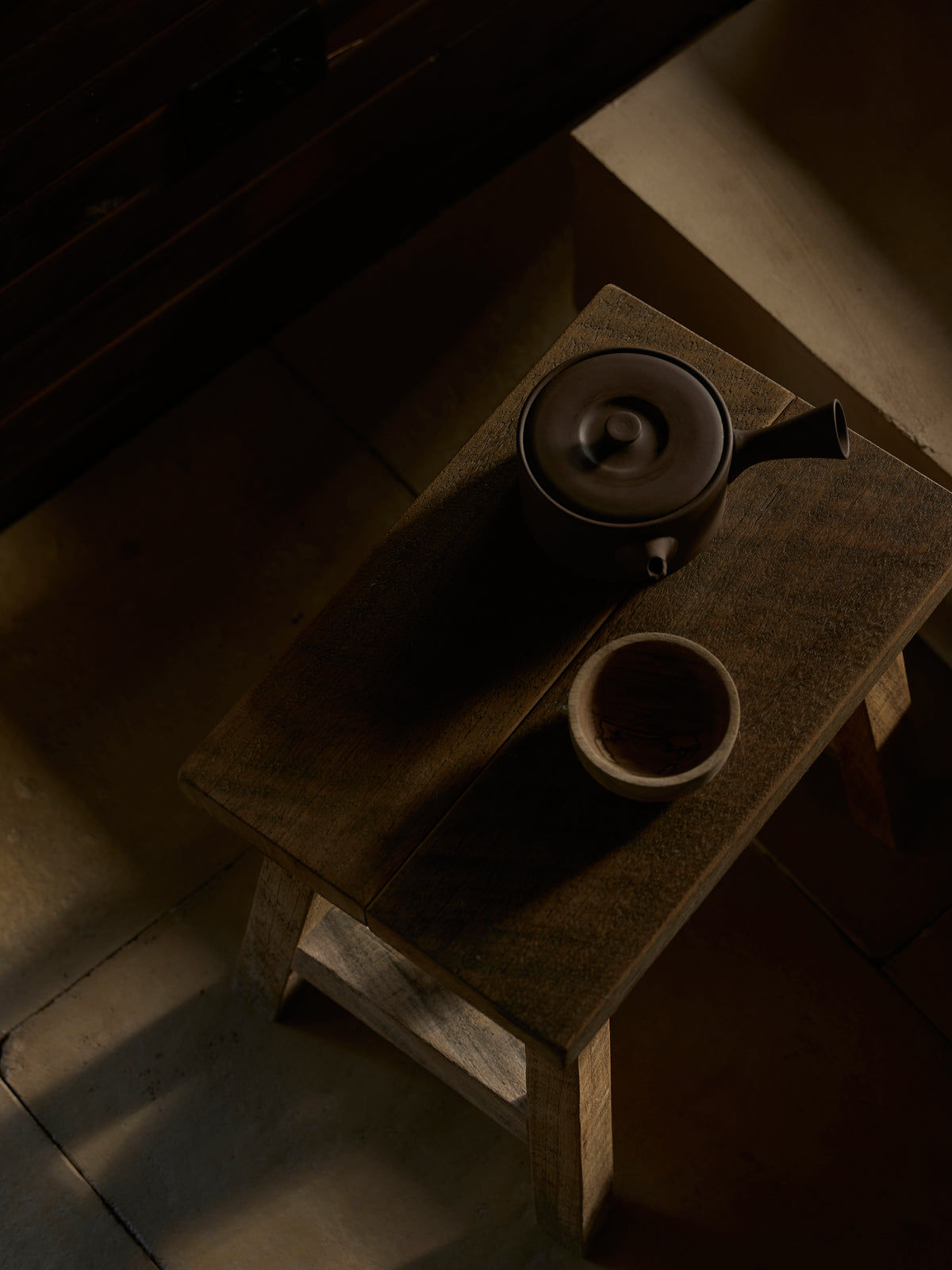 Tea set on a wooden table with a dark, moody atmosphere