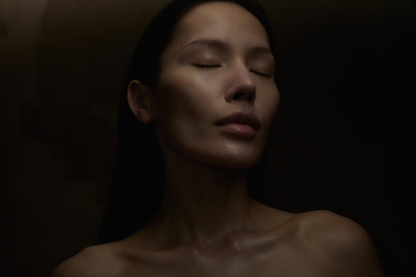 Woman with closed eyes against a dark background