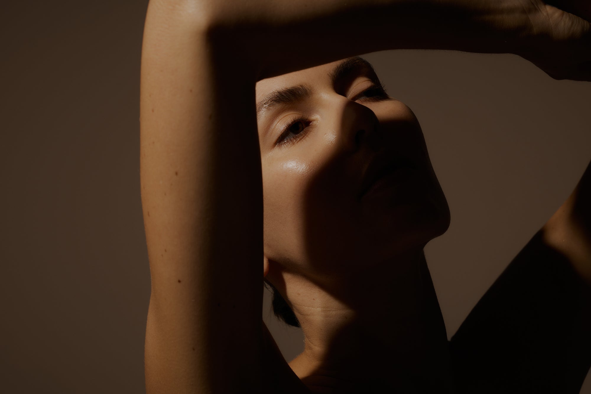 Person with arms raised against a brown background
