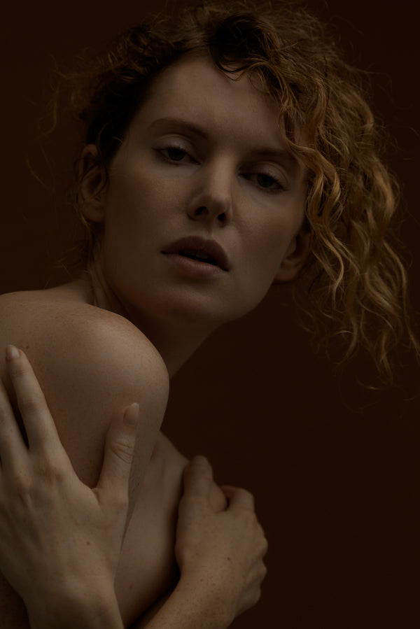 woman with curly red hair against a dark background