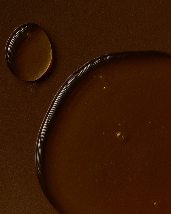Close-up of a brown surface with a droplet and a curved line.