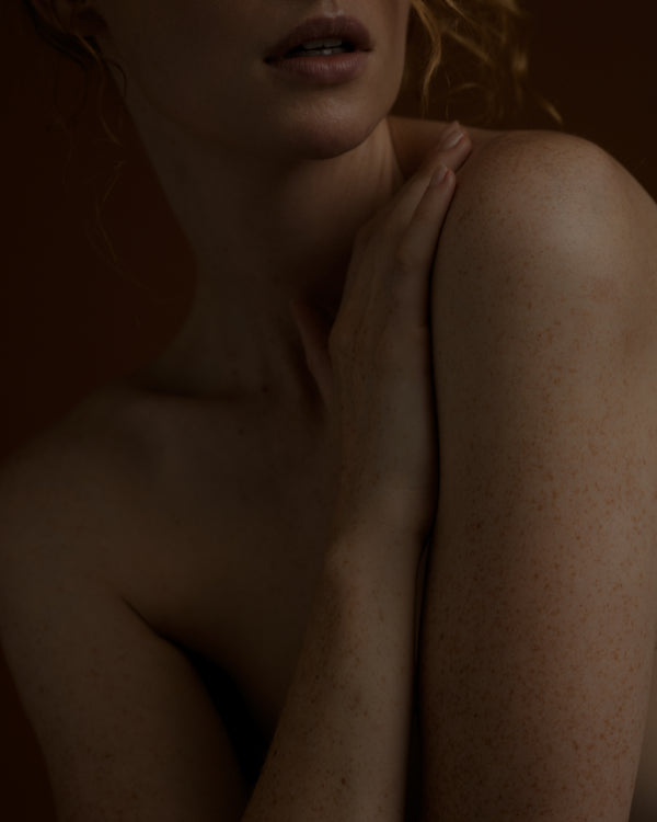 Woman holding shoulder against a dark background