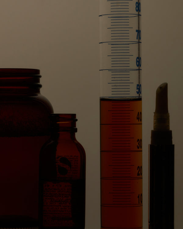 Amber glass bottles and a measuring cylinder on a white background