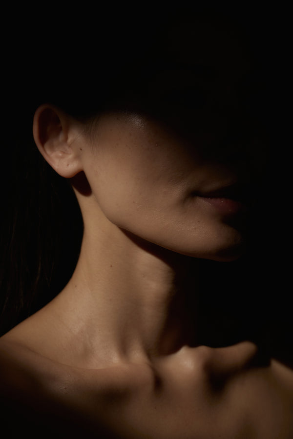 Close-up of a person's neck and shoulder against a dark background