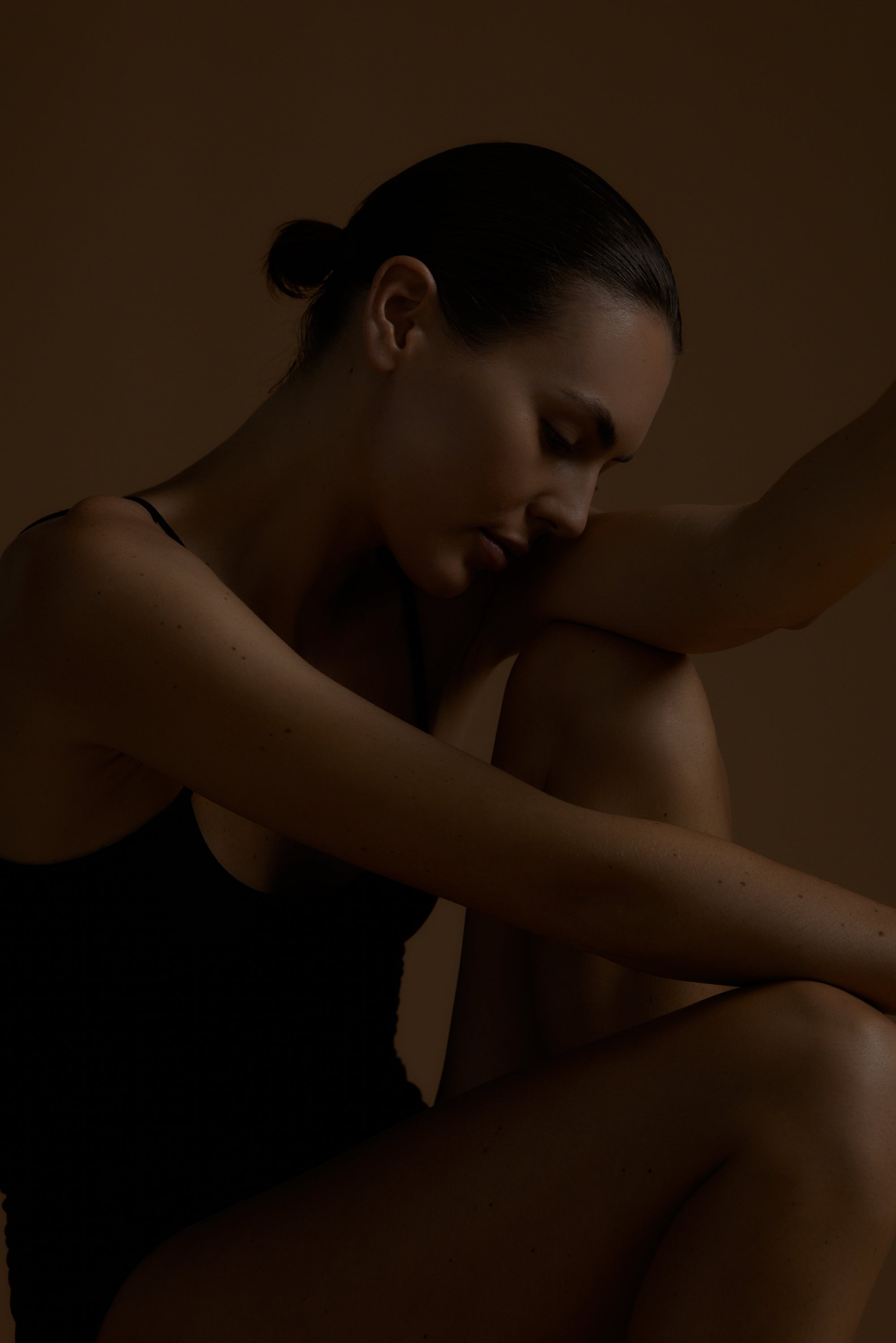 Woman sitting with her head in her hands against a dark background