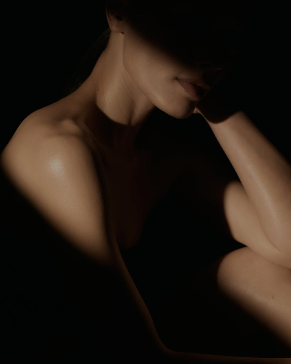 woman sitting with head in hands against a dark background