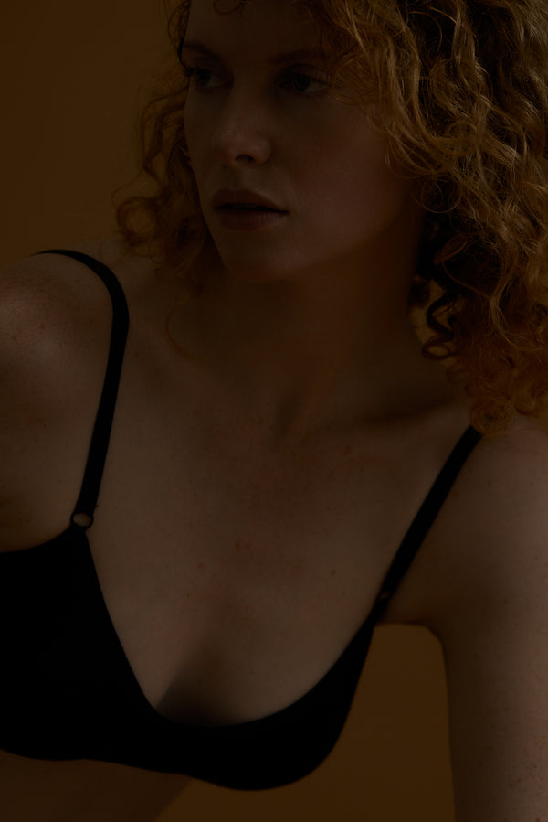 Woman wearing a black bra against a dark background