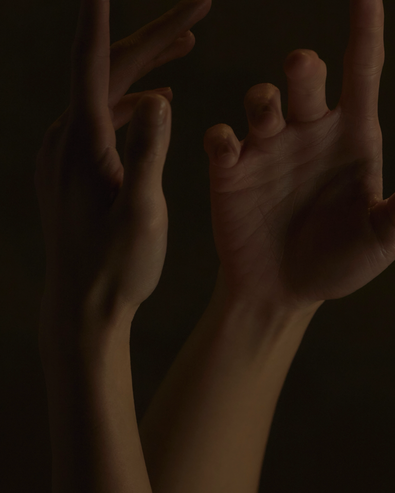 Two hands reaching towards each other against a dark background