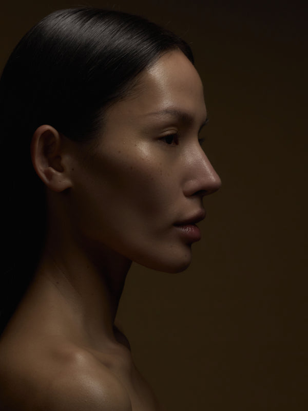 Side profile of a woman with dark hair against a brown background