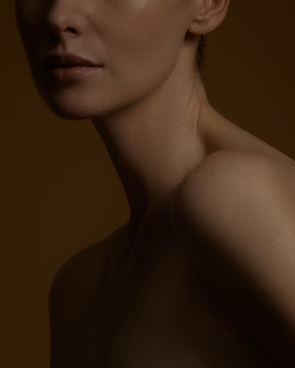 Woman against a brown background neck and shoulder