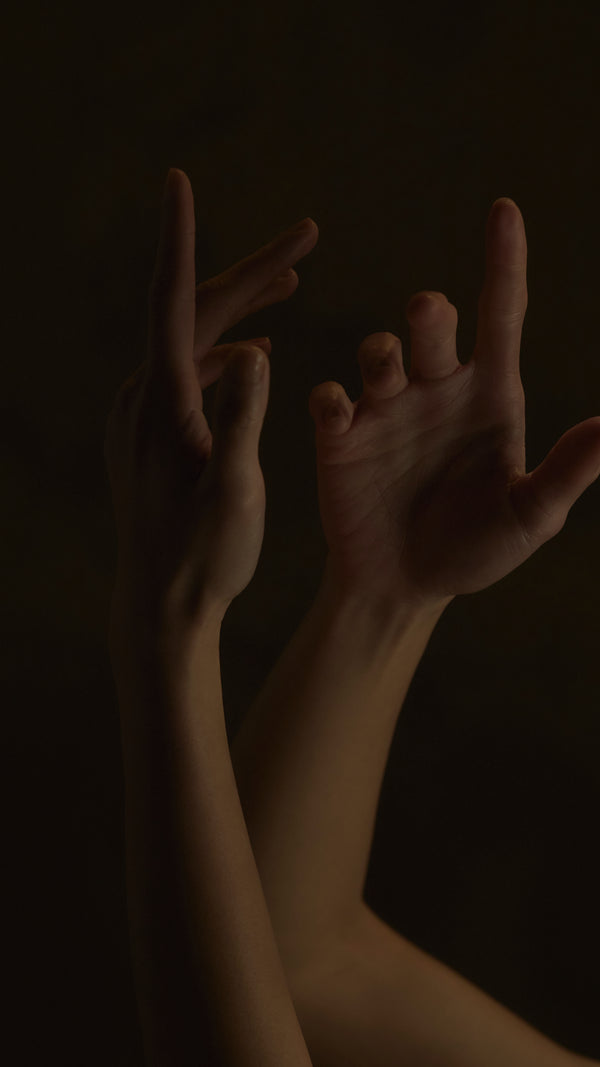 Two hands reaching towards each other against a dark background