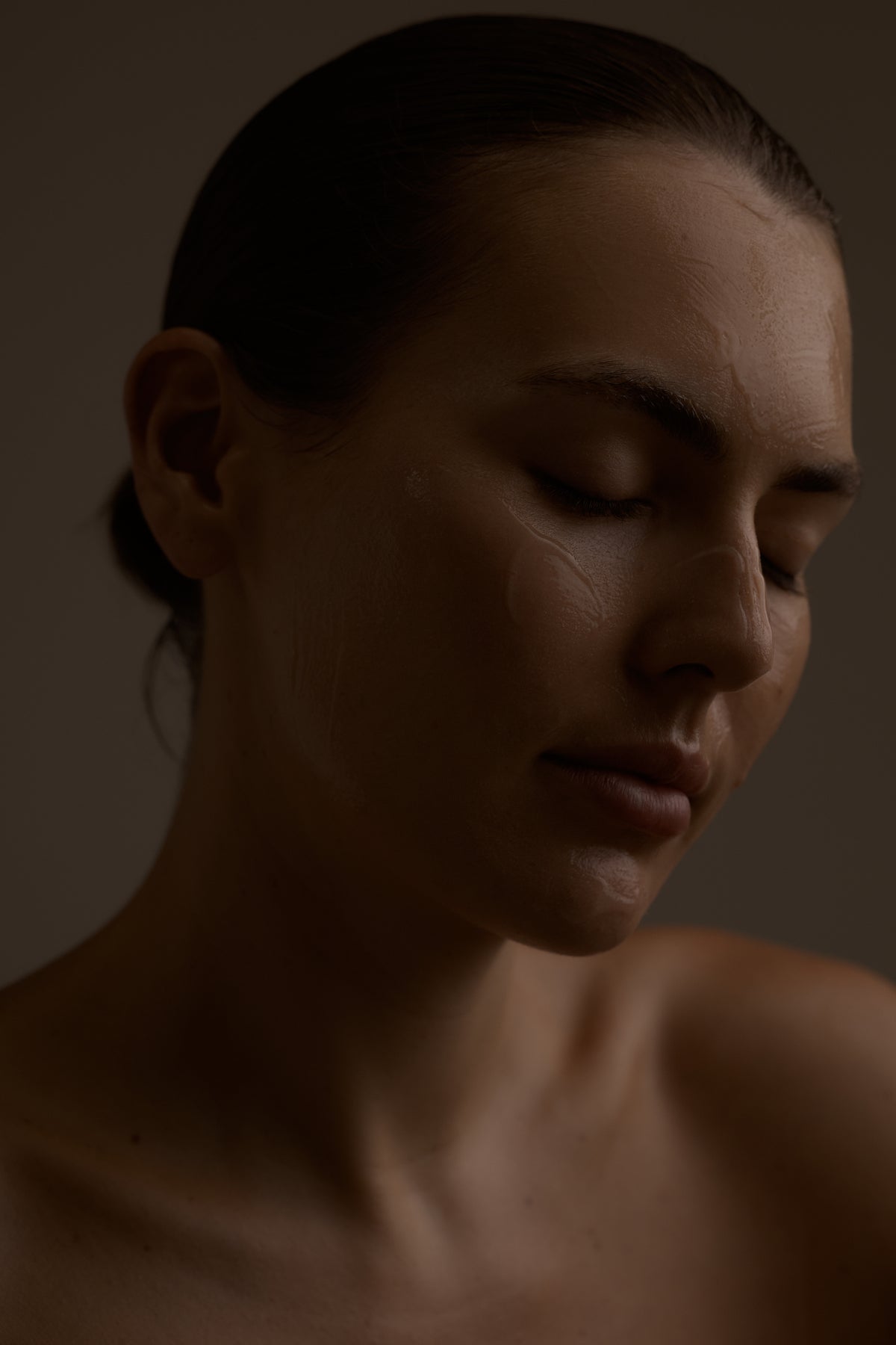 Dark portrait of a woman with a neutral expression on a brown background