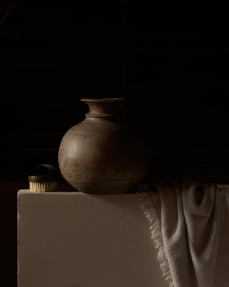 Brown ceramic pot on a white pedestal with a dark background