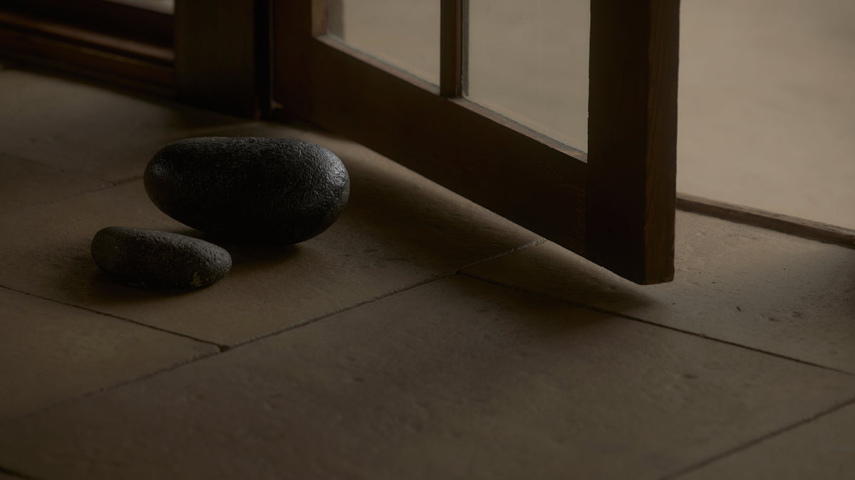 Two stones on a wooden floor next to a glass door