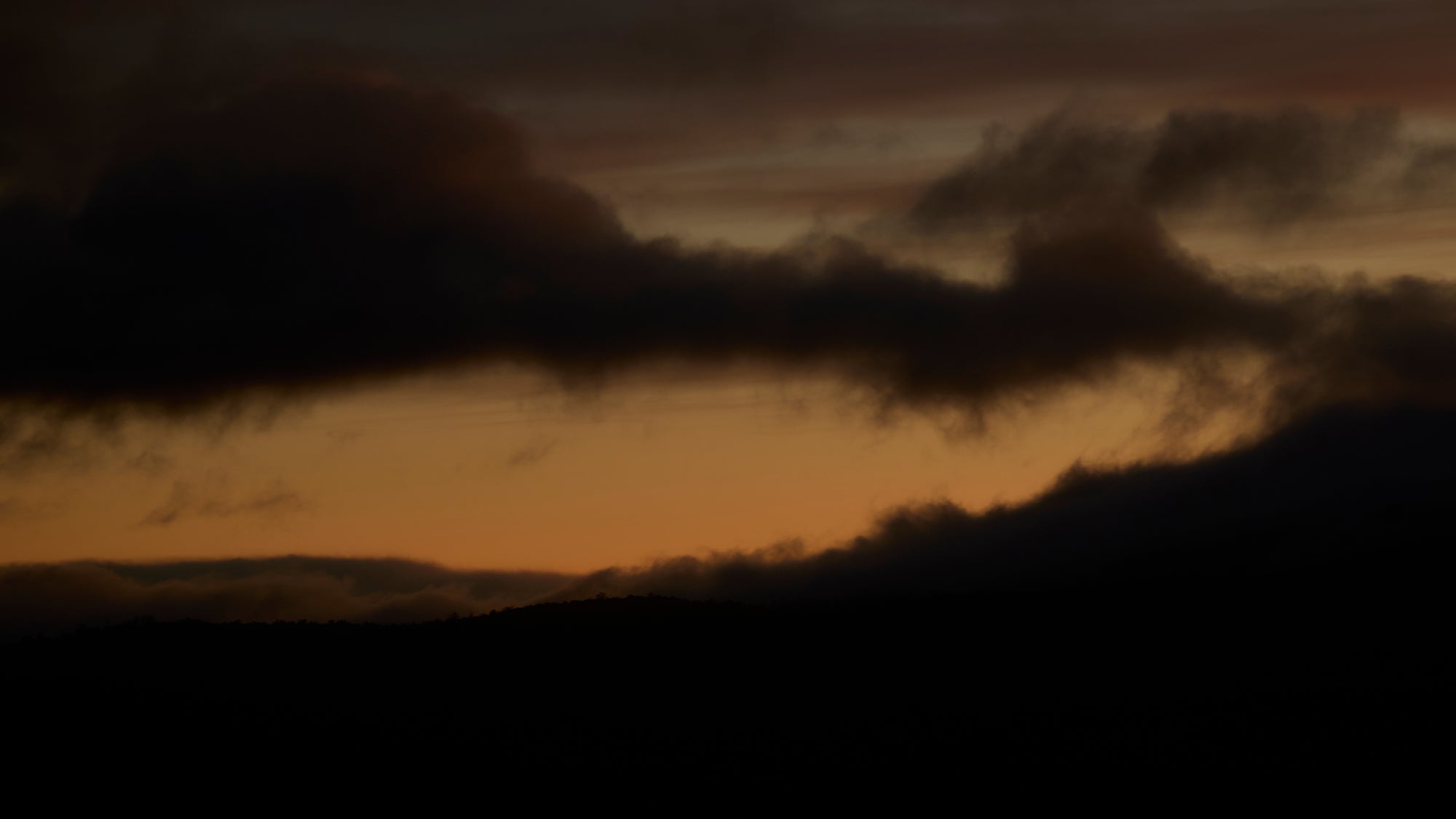 Dark clouds against an orange sunset sky