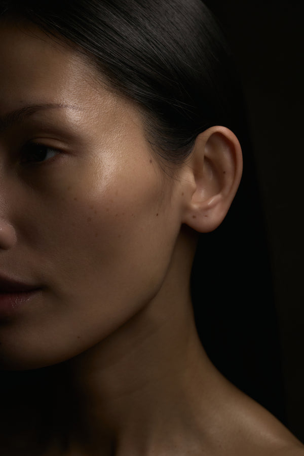 Close-up of a person's ear and neck with a dark background