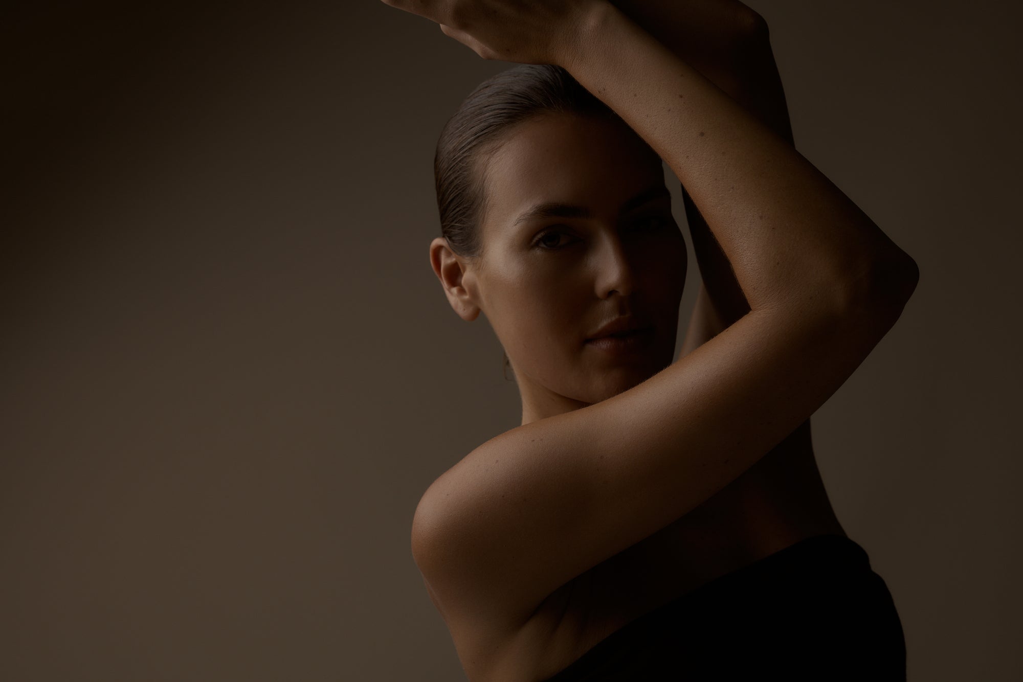 Woman with bare shoulders against a dark background