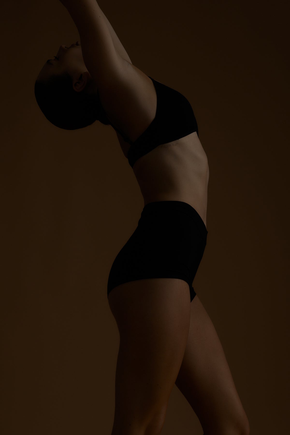 Person wearing black underwear against a dark background