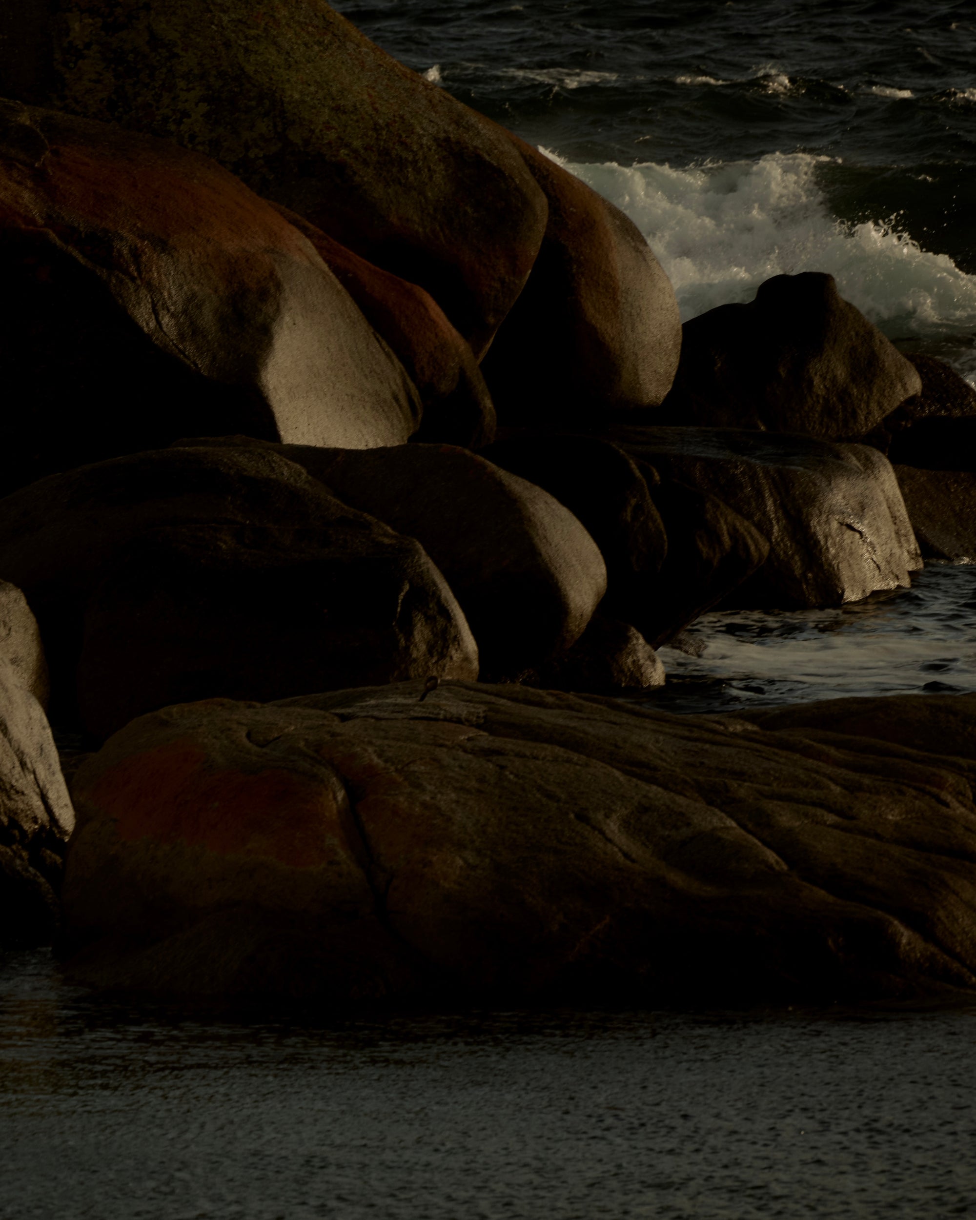 Rocks on a beach on sunshine coast with waves crashing against them.