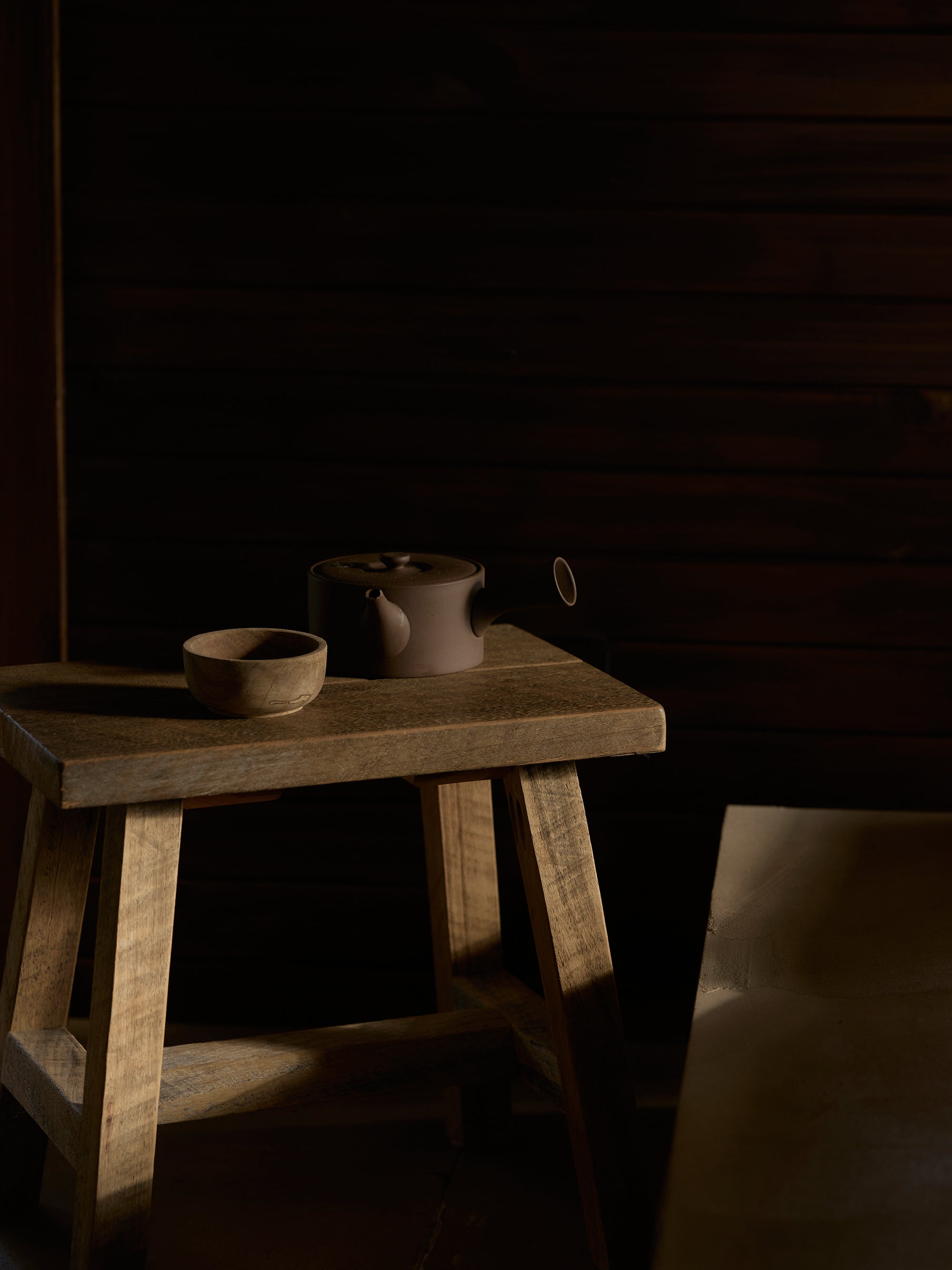 Teapot and tea bowl on a wooden stool in treatment room.